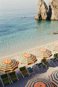Rows of striped umbrellas on a Mediterranean beach.