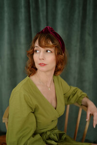 a woman in a green dress seated in a chair