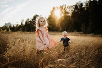 Blond hair toddler and her little brother standing on a filed in Portland, Oregon during sunset