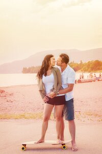 Couple on a long board at a Vancouver beach just about to kiss at sunset.