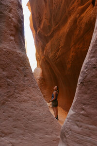 Brisa stands in Utah slot canyon looking up at the sky.