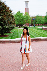 College senior laughing on the Belmont campus wearing her Master's cords