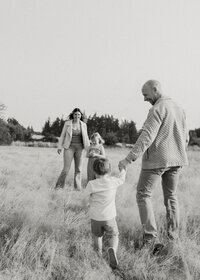 family holding hands walking in field of grass