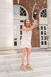 Senior girl popping champagne on the steps of Vanderbilt building