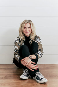 Kristin Tibbs, Northern Colorado real estate agent, sitting at desk and smiling while helping clients navigate high-stakes property decisions.