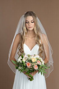 Bride wearing a two layer fingertip length veil with delicate ribbon edge