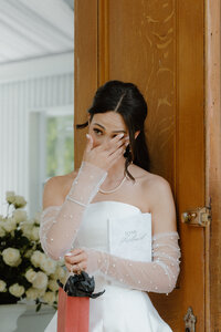 Emotional photo of bride wiping tears from her eyes while receiving a gift from her groom