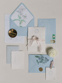 A blue wedding invitation suite flat lay with dainty and feminine touches.