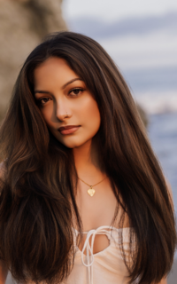 high school senior girl with long dark hair and brown eyes looking at camera at her senior session at the beach with renee bowen