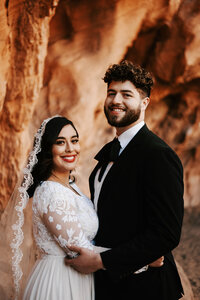 Bride and Groom eloping in Arches National Park in a wedding dress and black suit with a wedding arch.