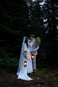 A couple in wedding attire holding lanterns and swaying together
