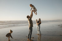 family plays on san diego beach with their children for family pictures