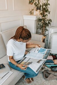 Woman holding a travel guide sitting on her couch