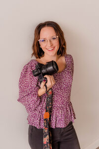 Rachel Hahn, owner of Rachel B  Photography, smiles at the camera with her laptop open.