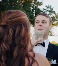 Playful snapshot from a Boston wedding film showing the bride offering the groom a sip of her drink