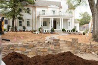 Front yard landscaping in progress at a white brick home with a curved stone walkway, Better Lawns and Gardens team planting flowers and shrubs in Little Rock, Arkansas.
