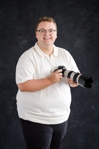 Man holds camera ready to take senior portraits