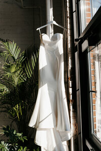 A wedding dress hanging by a window at PAIKKA which is a wedding venue in Saint Paul Minnesota, taken by Lulle Photo a minneapolis wedding photographer