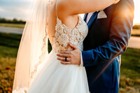 Bride and groom wedding standing together dancing in front of sun flare