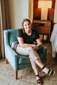 woman sitting in a blue chair smiling with her legs crossed