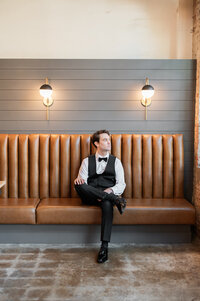 A person sitting on a brown leather couch with one leg on their knee