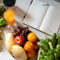 Fruits and vegetables sitting next to a journal
