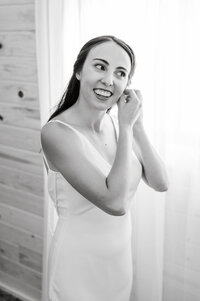 bride fastens her earrings while looking away from the camera