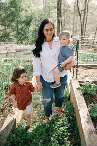 Woman walking through a vegetable garden with her two children