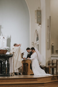 fallback shared on Invalid Date | a Catholic bride and groom being blessed by a priest
