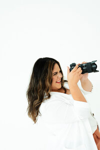 Adriana Montoya Photo lying on the ground with her arm propped up, holding her head up. Next to her on the ground is her camera.