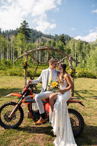 Bride and groom on dirt bike at wedding.