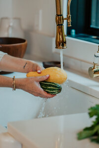 Sam washing squash in her kitchen sink