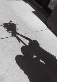 Shadows of a bride and groom holding a bouquet, cast onto the pavement during their Colorado wedding day.