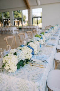 Southern garden-inspired Oklahoma wedding reception with a long table decorated in blue hydrangeas and elegant linens