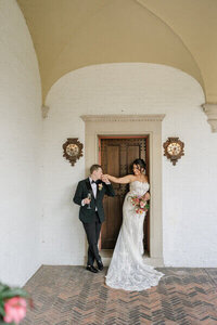 Bride and groom standing in front of doorway while groom kisses brides hand by Dream Weddings, Wisconsin wedding planner.