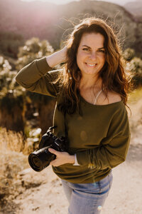 Jaime Bugbee, professional headshot photographer, posing with her camera