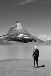 The girl is standing and looking at the mountain