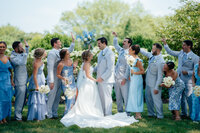 bride and groom surround by a celebrating wedding party after they just got married