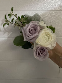 Hand holding a small bouquet with lavender and white roses