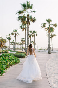 Wedding portrait of a bride walking down a beach. Dubai beach wedding inspiration. Photo shoot organized by Lovely & Planned.
