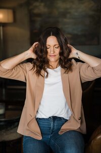 Woman sitting on a leather chair holding a camera, with a gentle smile, is an esteemed photography mentor.