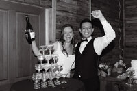 Bride and groom celebrating with a champagne tower pour during their Colorado wedding reception.