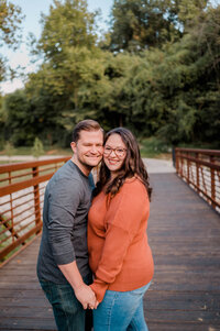 A couple stands cheek to cheek and smiles at the camera.