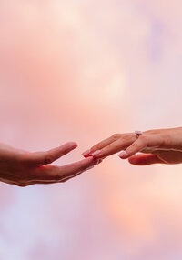 Close-up of couple’s hands reaching toward each other at sunset during their Colorado engagement session.