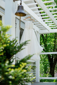 angled shot of a bride's wedding dress hanging from a trellis