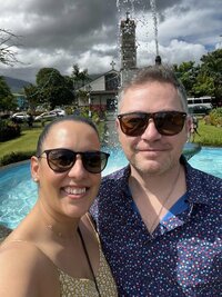 Two people smiling at the camera outside of a pool on vacation