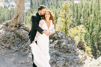 This image depicts a bride holding her groom's hand as they navigate through rocky terrain at the Peyto Lake viewpoint in Banff National Park. The couple’s journey through the rugged landscape symbolizes their commitment to walk through life together, set against the stunning backdrop of the lake's vibrant turquoise waters.