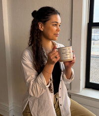 artist smiling and holding a bible verse mug