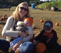 Maureen sitting in pumpkin patch with 3 year old son and 3 month old