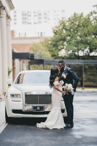 bride and groom standing in front of white car